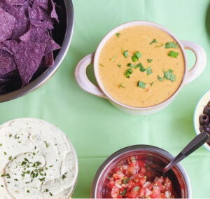 Nacho bar with blue tortilla chips, cheese con queso, Sour Cream, fresh salsa